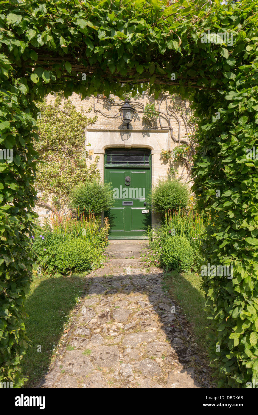 Long stone garden path leading to front door of house under beech arch, England, UK Stock Photo