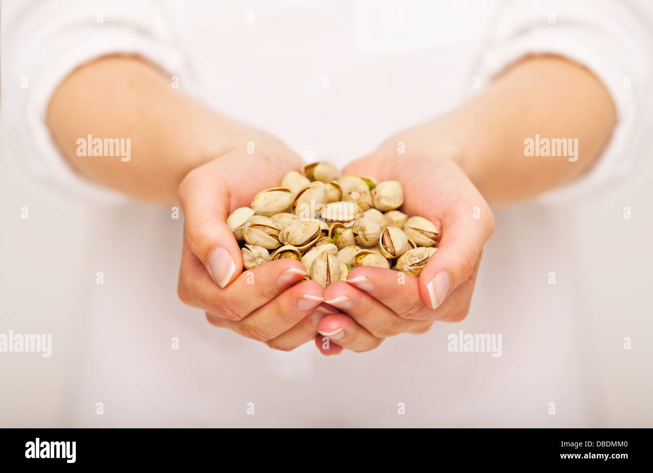 Woman offering a handful of pistachio nuts Stock Photo