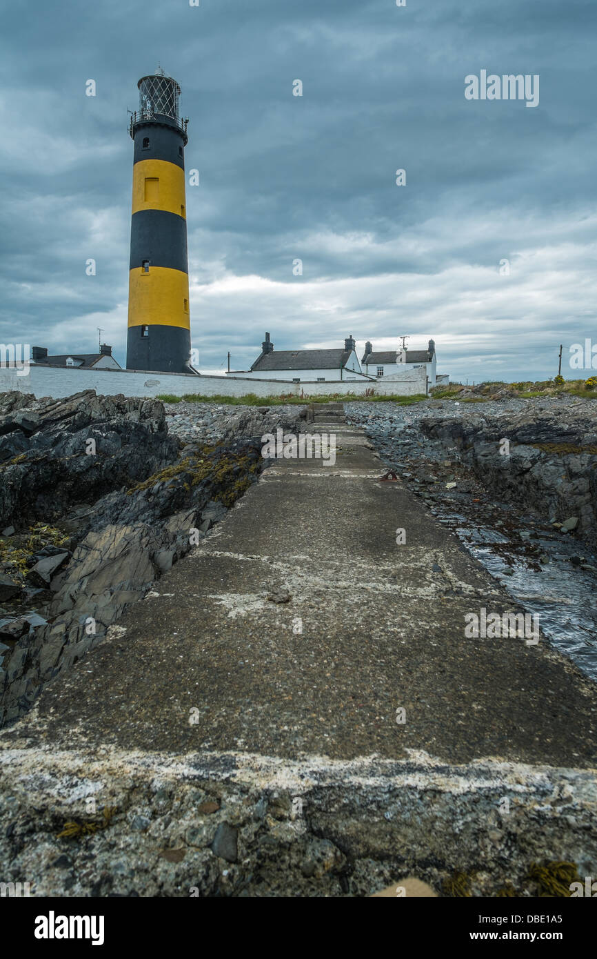 St John's Point Lighthouse in County Down Northern Ireland shown against stormy gray clouds, photograph taken from a concrete dr Stock Photo