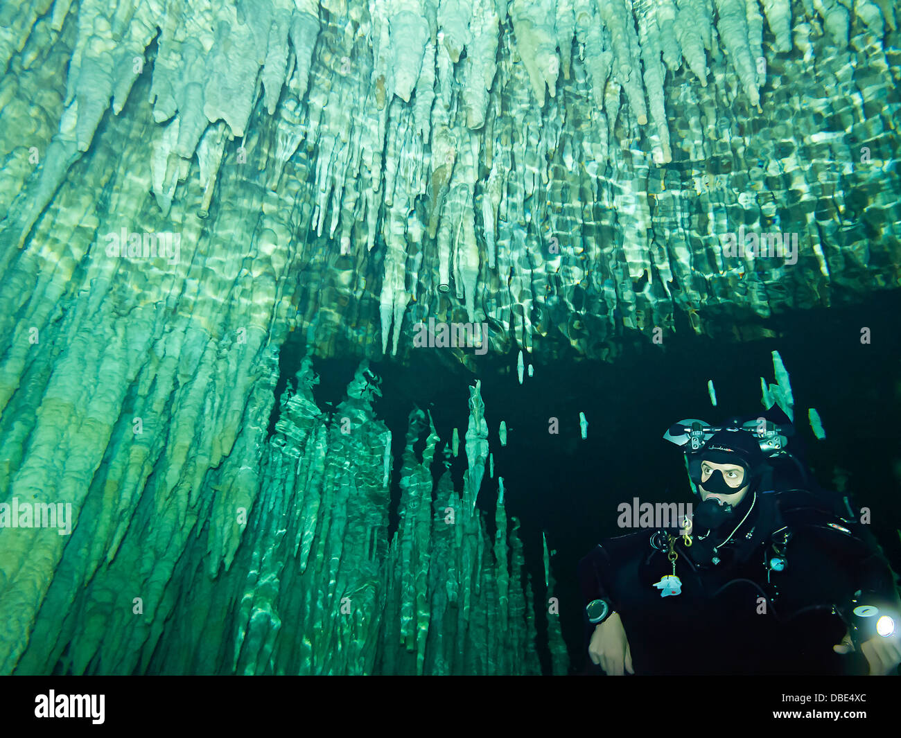 Diver with stalactite spikes hanging from ceiling of Dream Gate, one of the many cenotes people scuba dive in Yucatan, Mexico Stock Photo