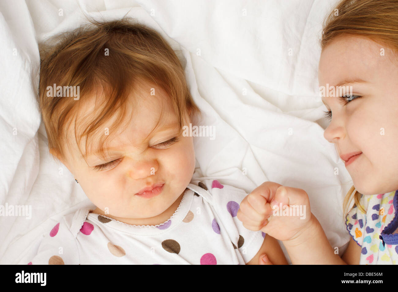 Silly baby in sheets with big sister Stock Photo