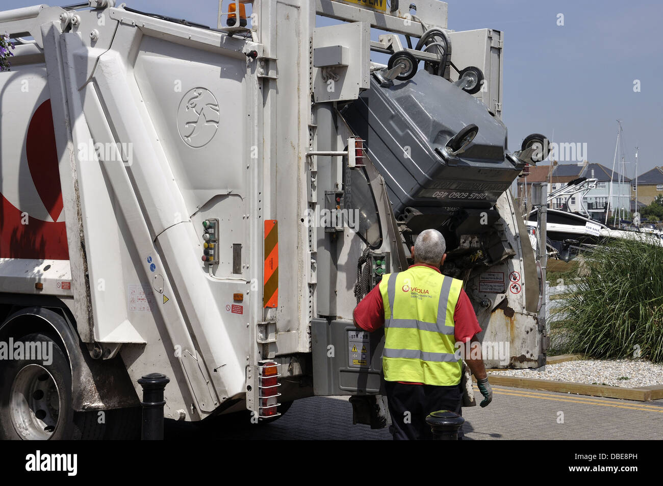 Refuse wagon with commercial bin being emptied by yellow jacketed