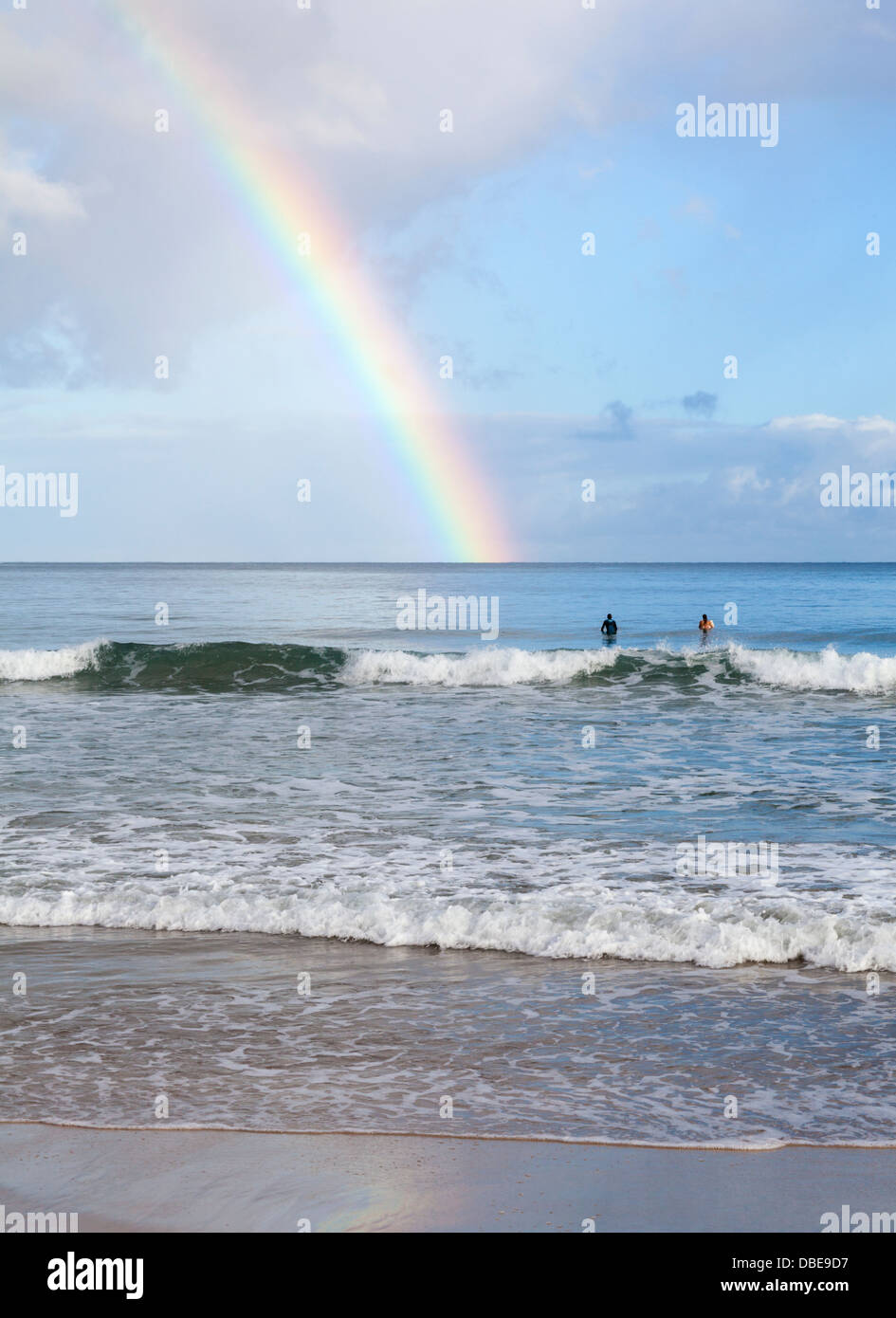 Surfers in Hanalei Bay on Kauai admire rainbow Stock Photo