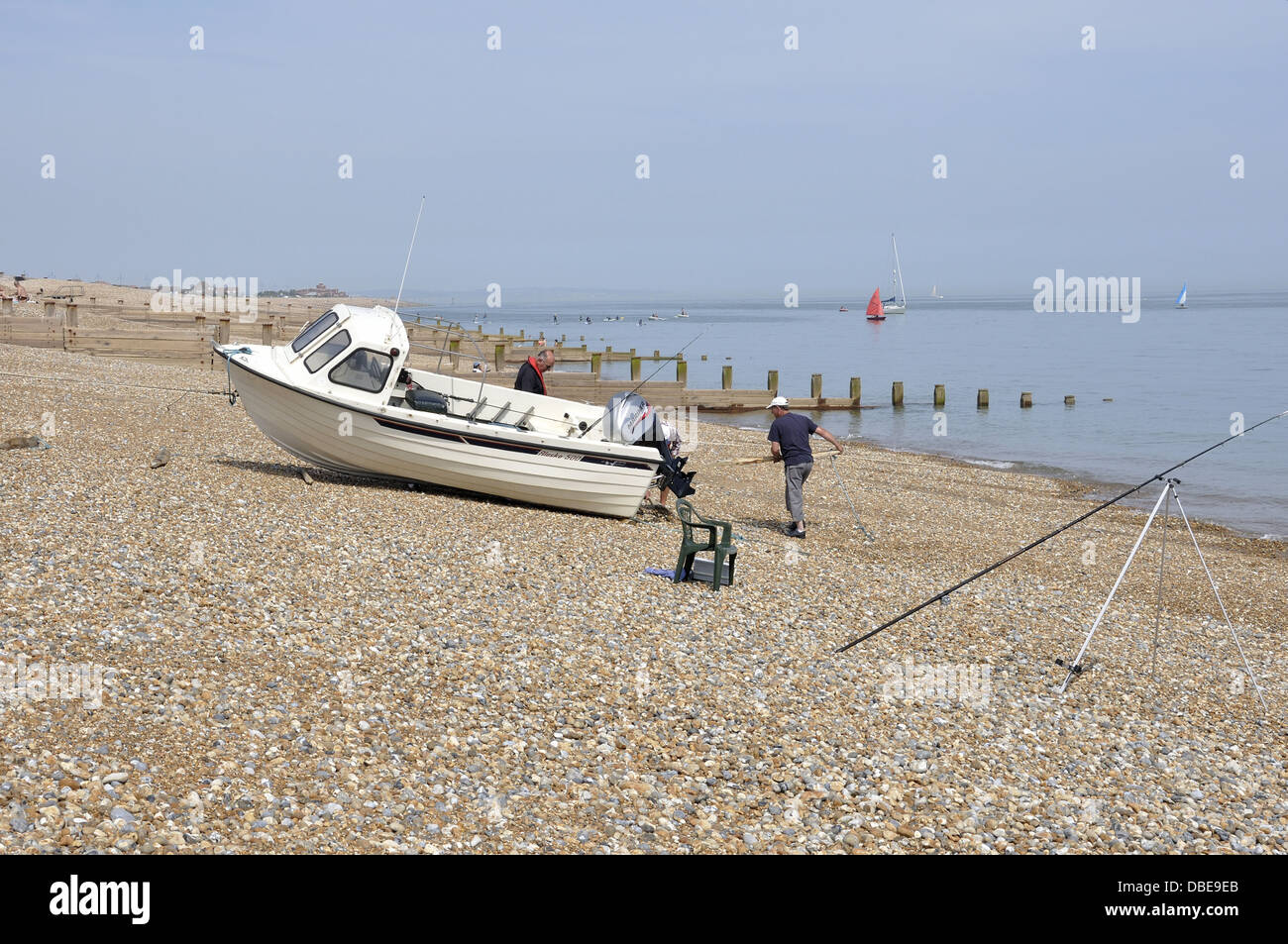 Winching boat on rollers from sea across shingle beach Stock Photo