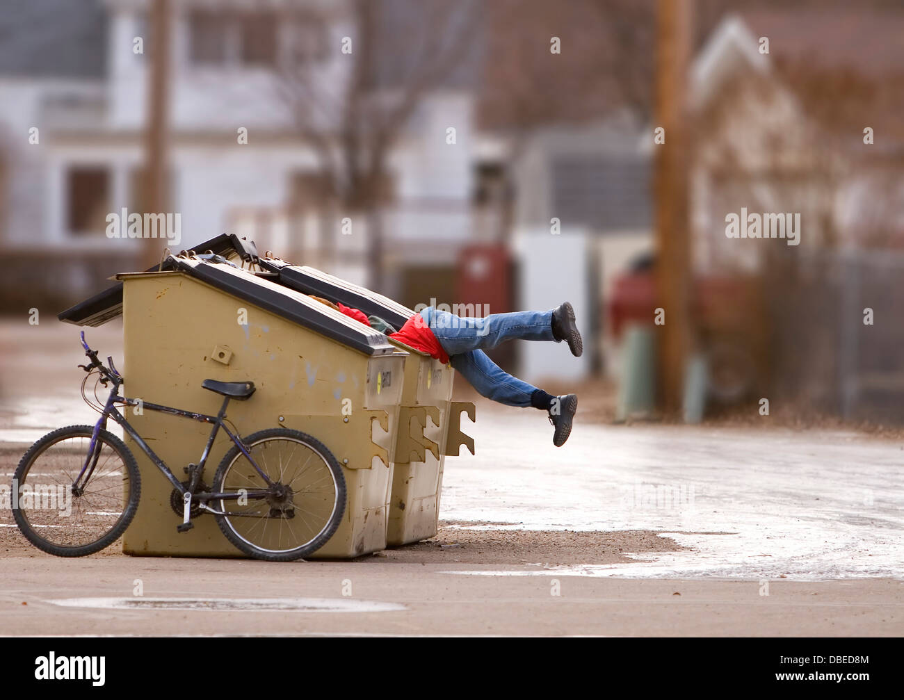 Homeless man with a bike looking in a dumpster Stock Photo Alamy