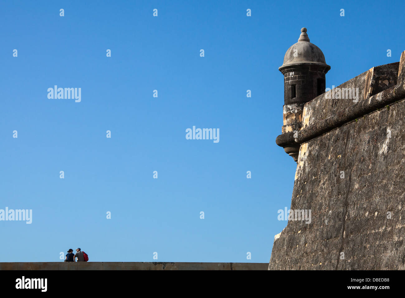 A couple sits on the wall of El Morro Fort, San Juan, Puerto Rico. Stock Photo