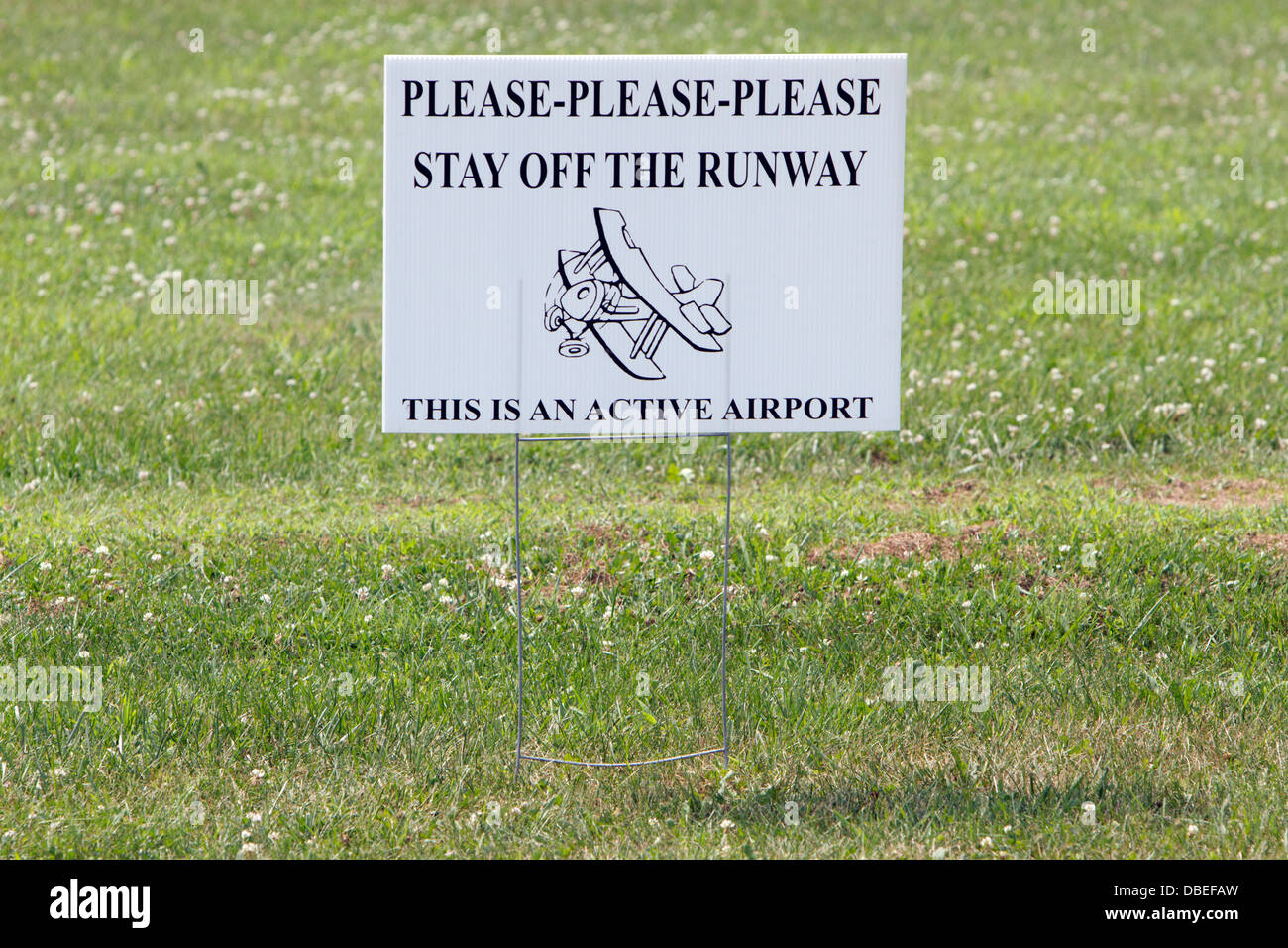 Sign warning people not to walk on an airplane runway. Stock Photo