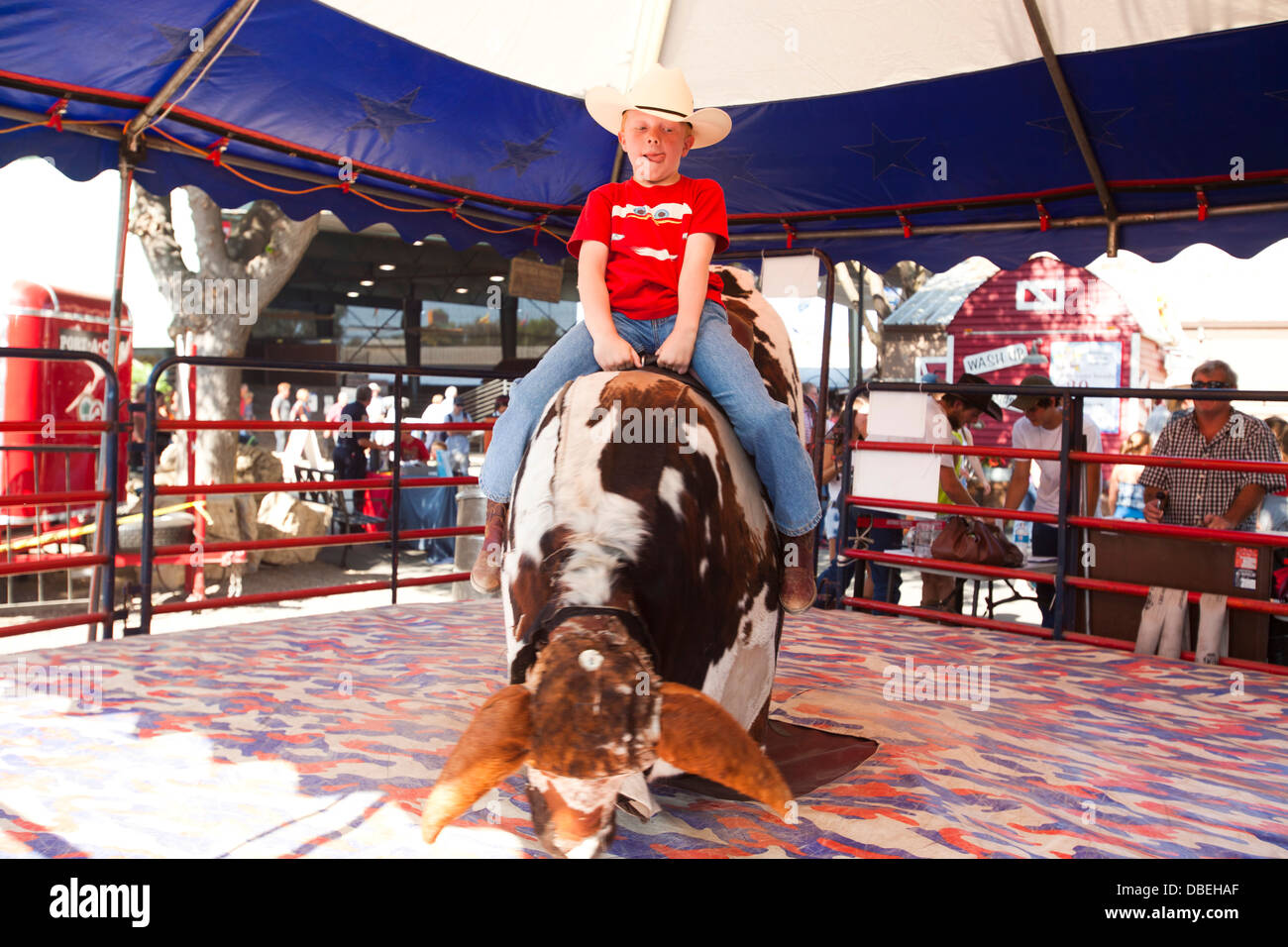 Young Cowboy riding a mechanical bull. California Mid State Fair, Paso Robles, California, United States of America Stock Photo