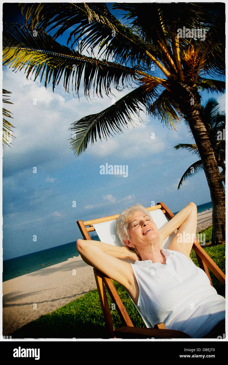 Older woman relaxing on tropical beach - Smartphone Captured Stock Image