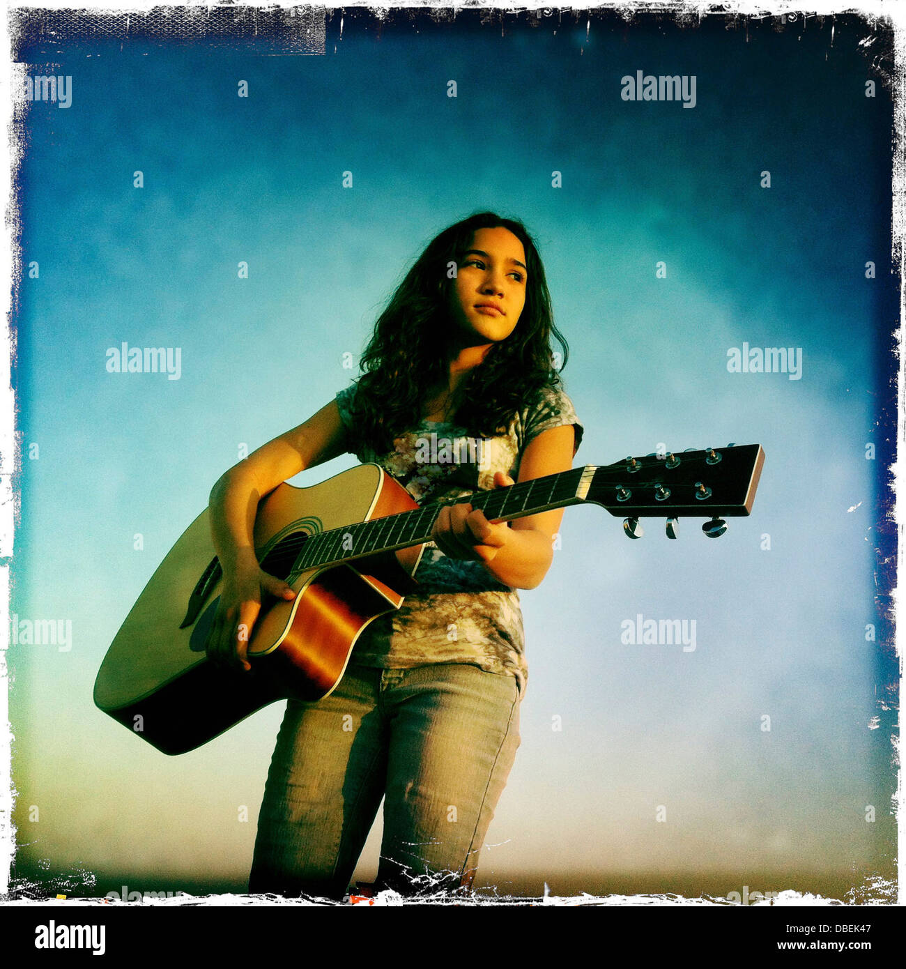 Hispanic girl playing guitar outdoors Stock Photo