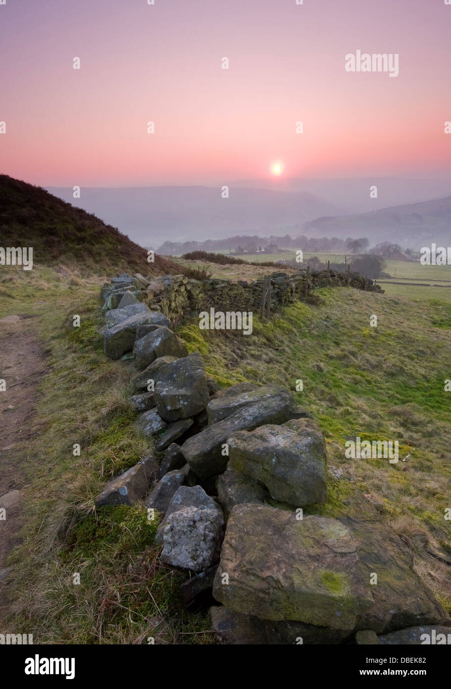 A typical Yorkshire dry stone wall leading the eye down towards a misty valley Stock Photo