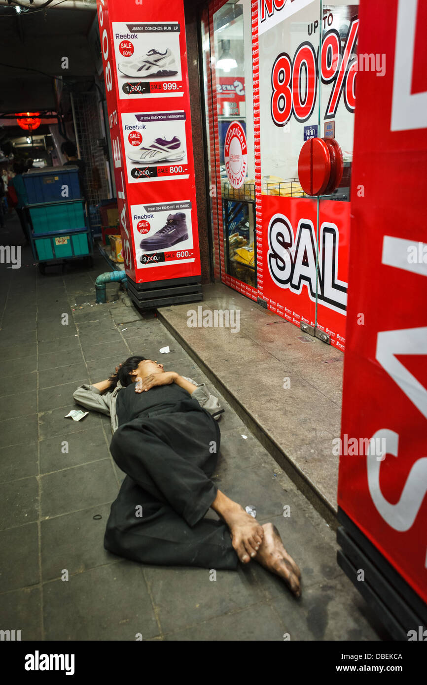 Unconscious Asian homeless male sleeping on the street Stock Photo
