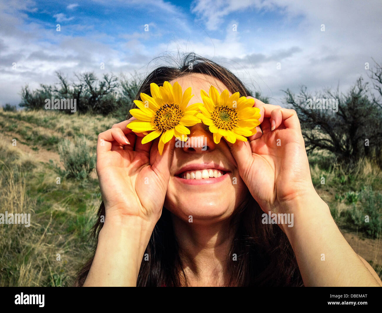 Caucasian woman holding flowers over her eyes - Smartphone Captured Stock Image