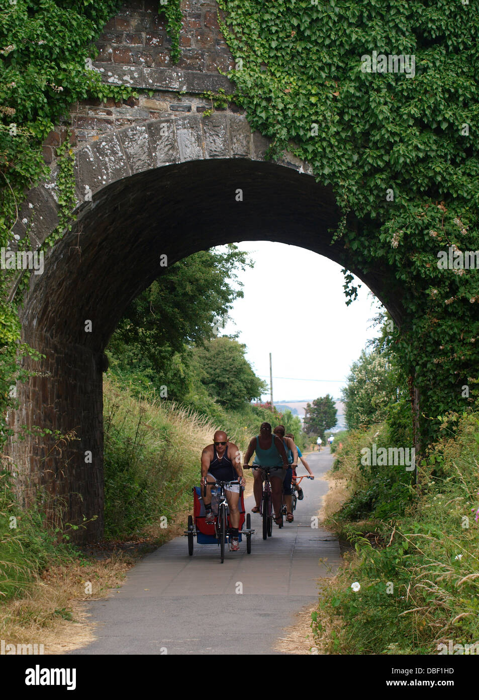 Family cycling under bridge on the Tarka Trail, Instow, Devon, UK 2013