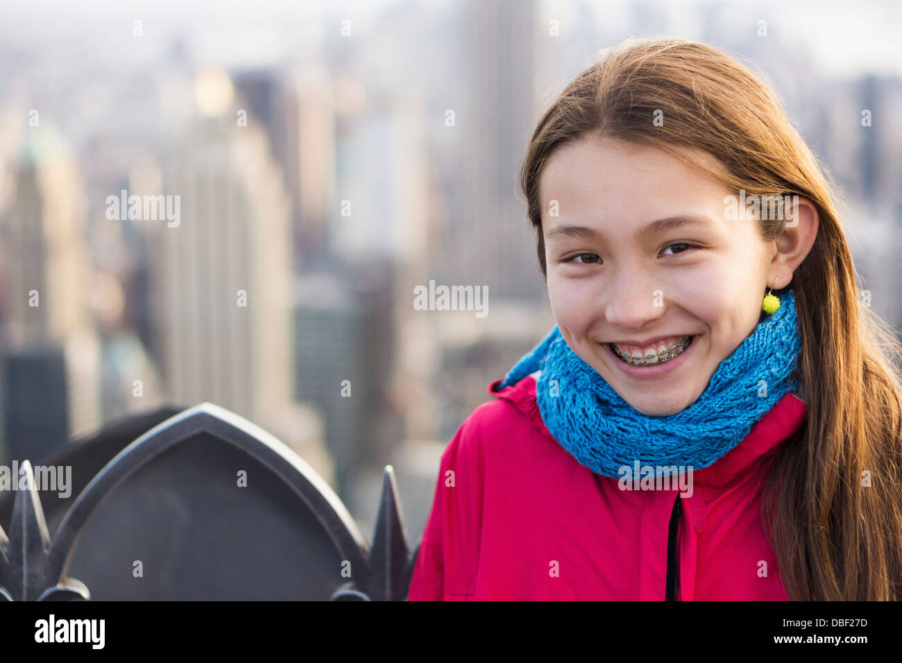 Mixed race girl smiling on urban rooftop Stock Photo