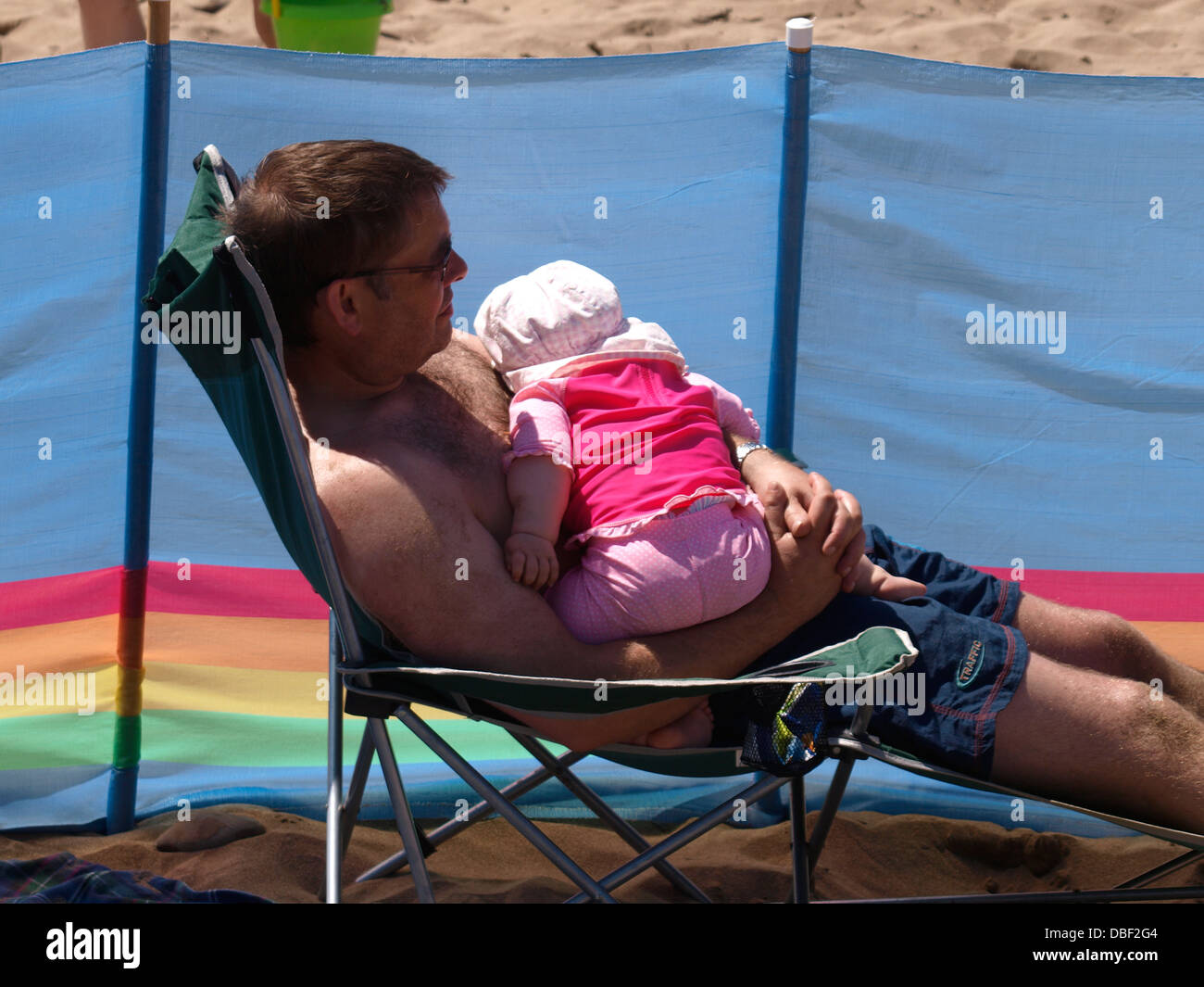 Man with cute baby asleep in his arms at the beach, UK 2013 Stock Photo