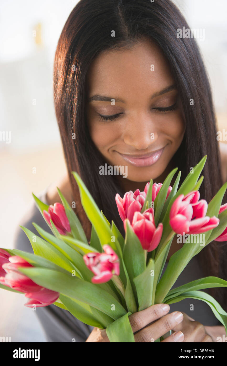 Mixed race woman smelling flowers Stock Photo