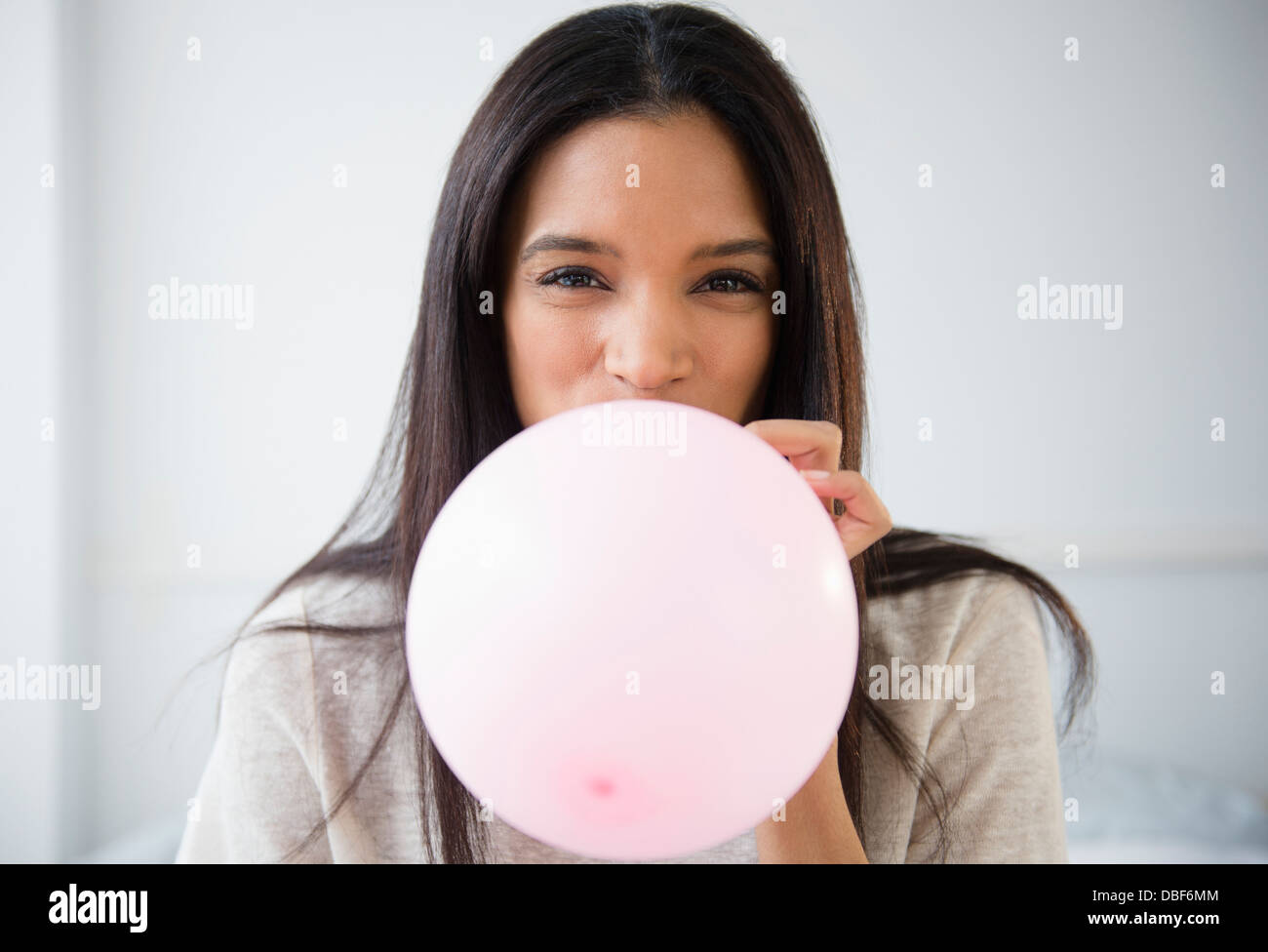 Mixed race woman blowing up balloon Stock Photo