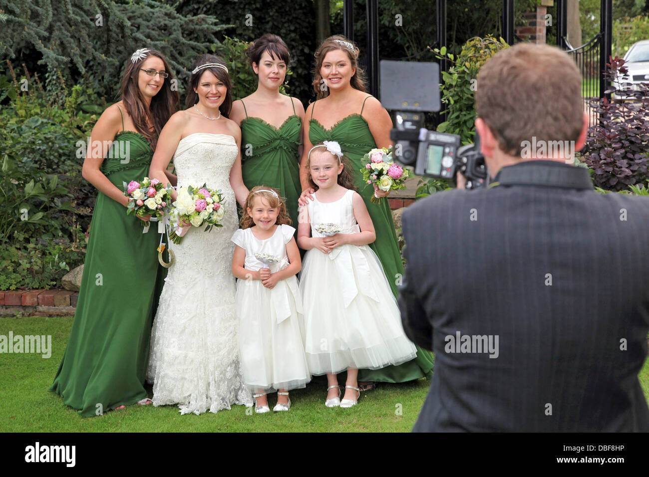 A Wedding photographer can be seen photographing a bride and her bridesmaids. Stock Photo