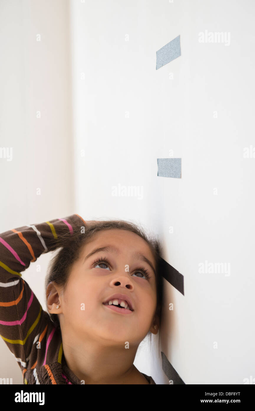 Hispanic girl measuring her height on wall Stock Photo