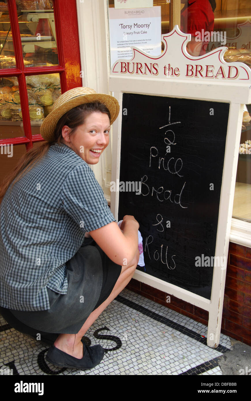 girl writing advertising board at Burns the baker's, Glastonbury High Street, United Kingdom Stock Photo