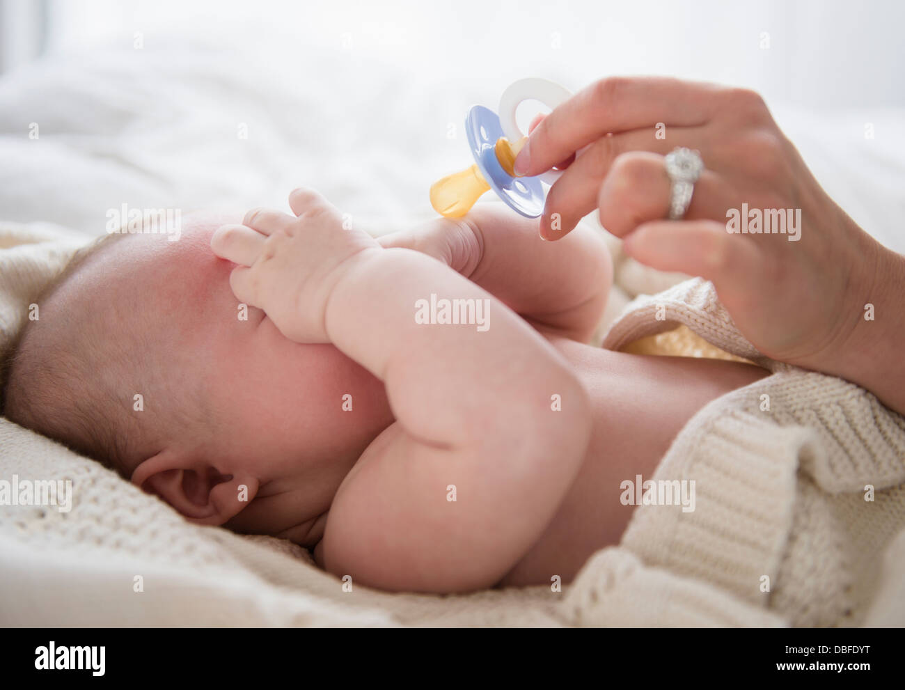 Caucasian mother giving baby pacifier Stock Photo