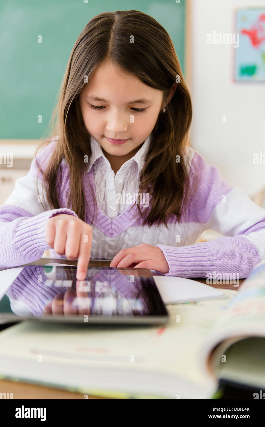 Mixed race girl using tablet computer in class Stock Photo