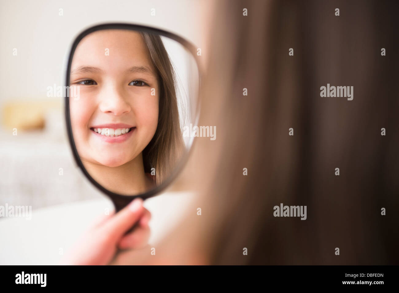 Mixed race girl admiring herself in mirror Stock Photo