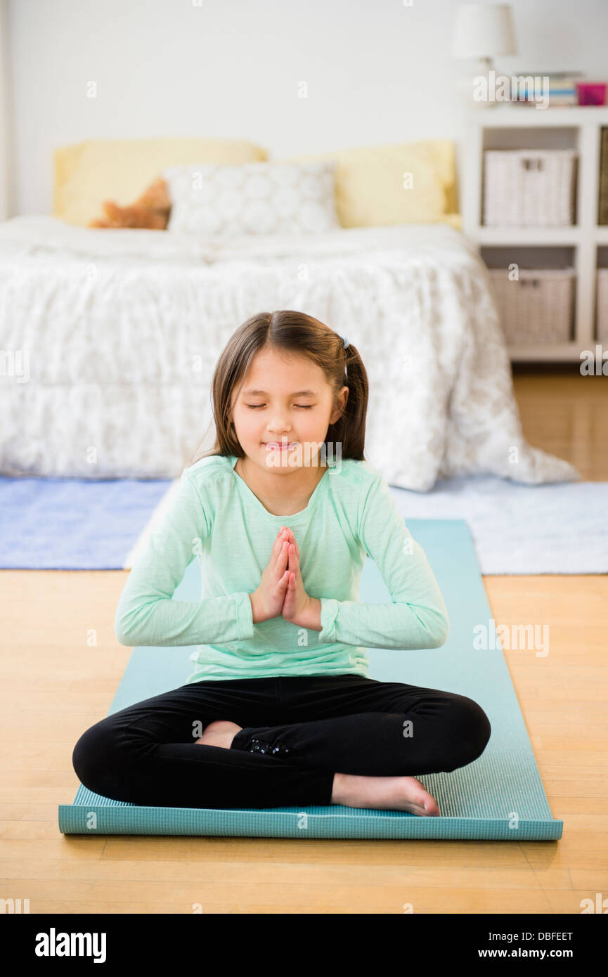 Mixed race girl meditating on yoga mat Stock Photo Alamy