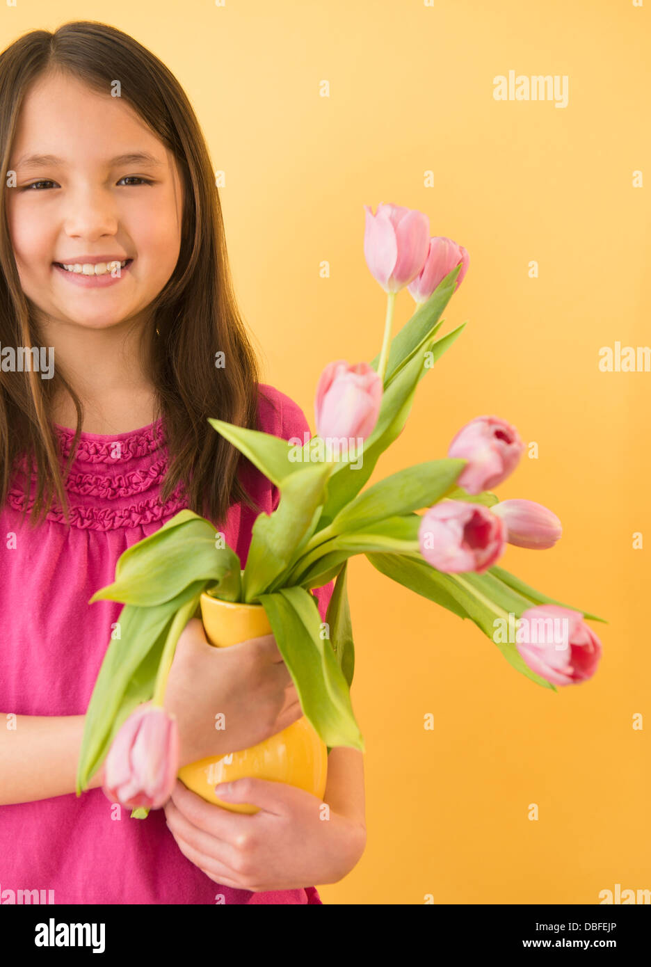 Mixed race girl holding vase of flowers Stock Photo