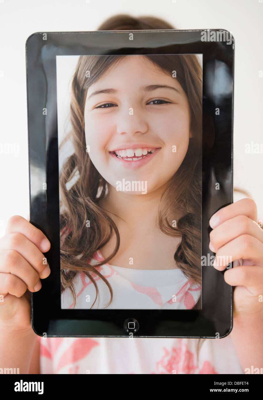 Hispanic girl holding tablet with picture of her face Stock Photo