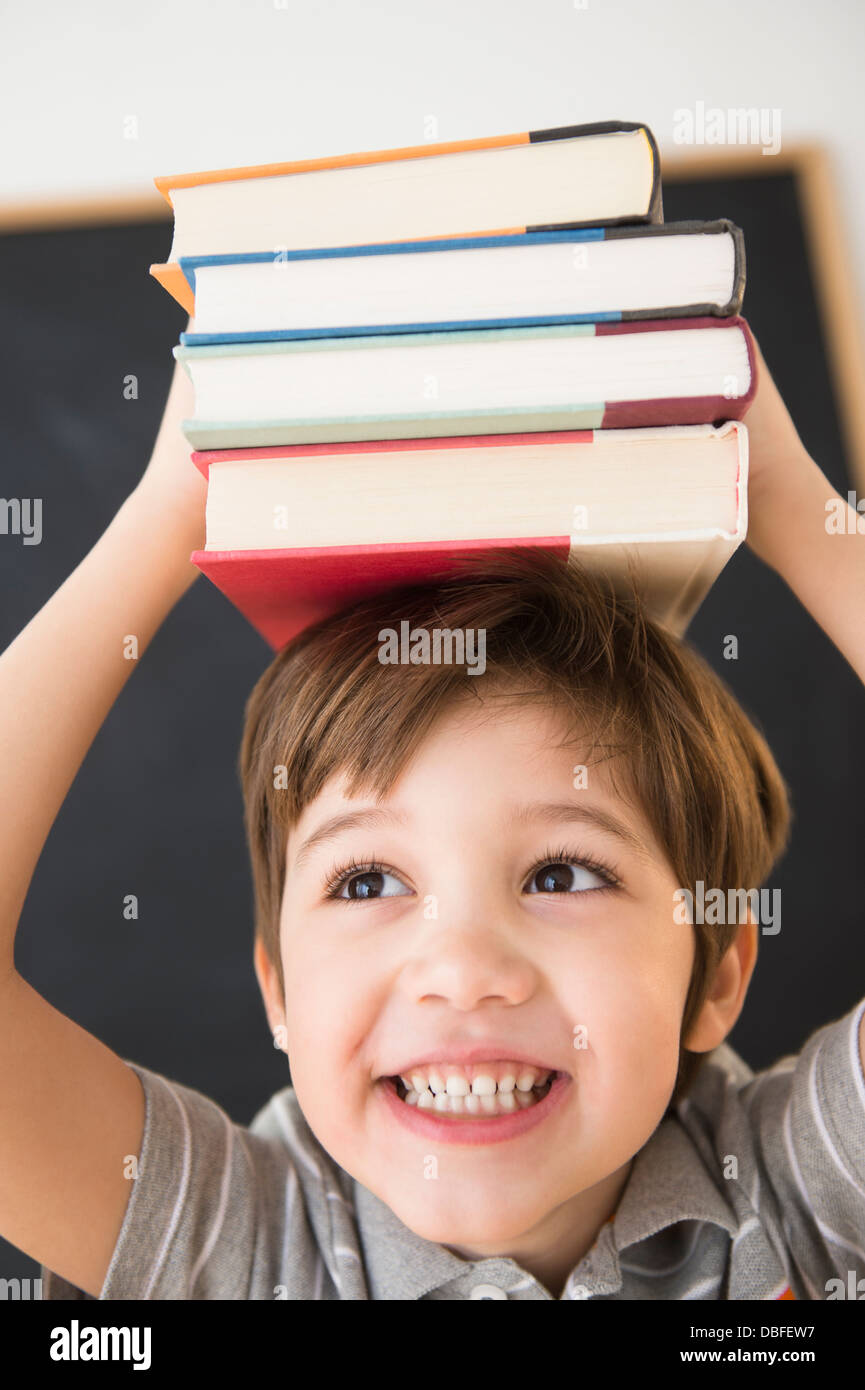 Hispanic boy balancing books on head Stock Photo