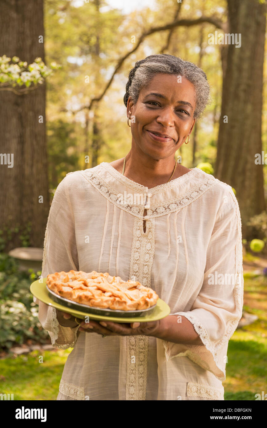 Mixed race woman holding fruit pie outdoors Stock Photo