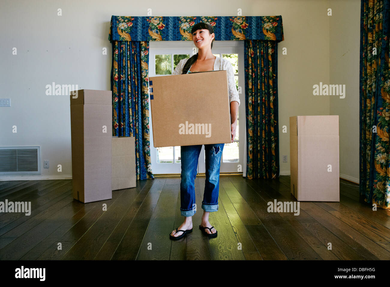 Mixed race woman carrying box in new home Stock Photo