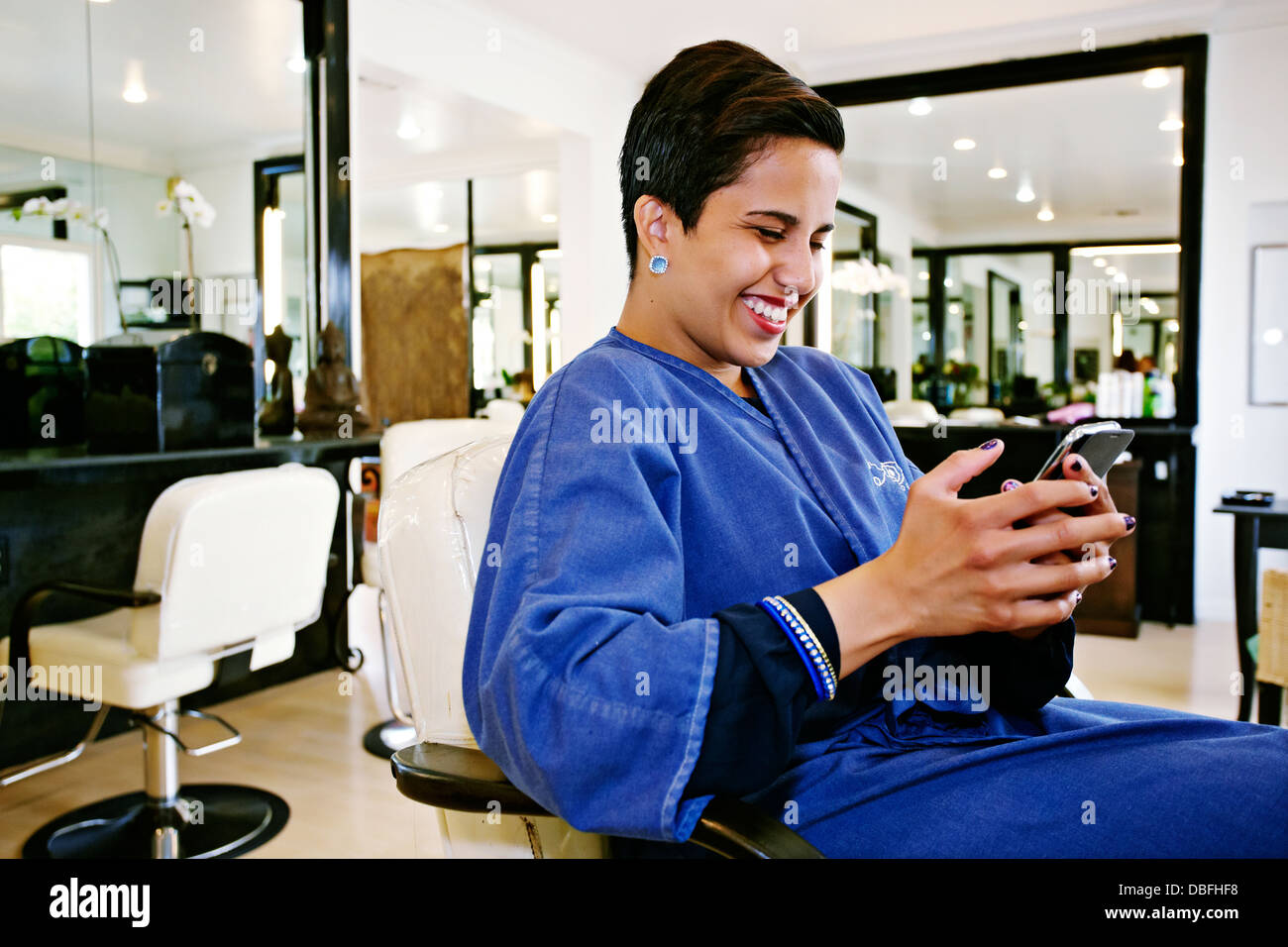 Hispanic woman using cell phone in salon Stock Photo