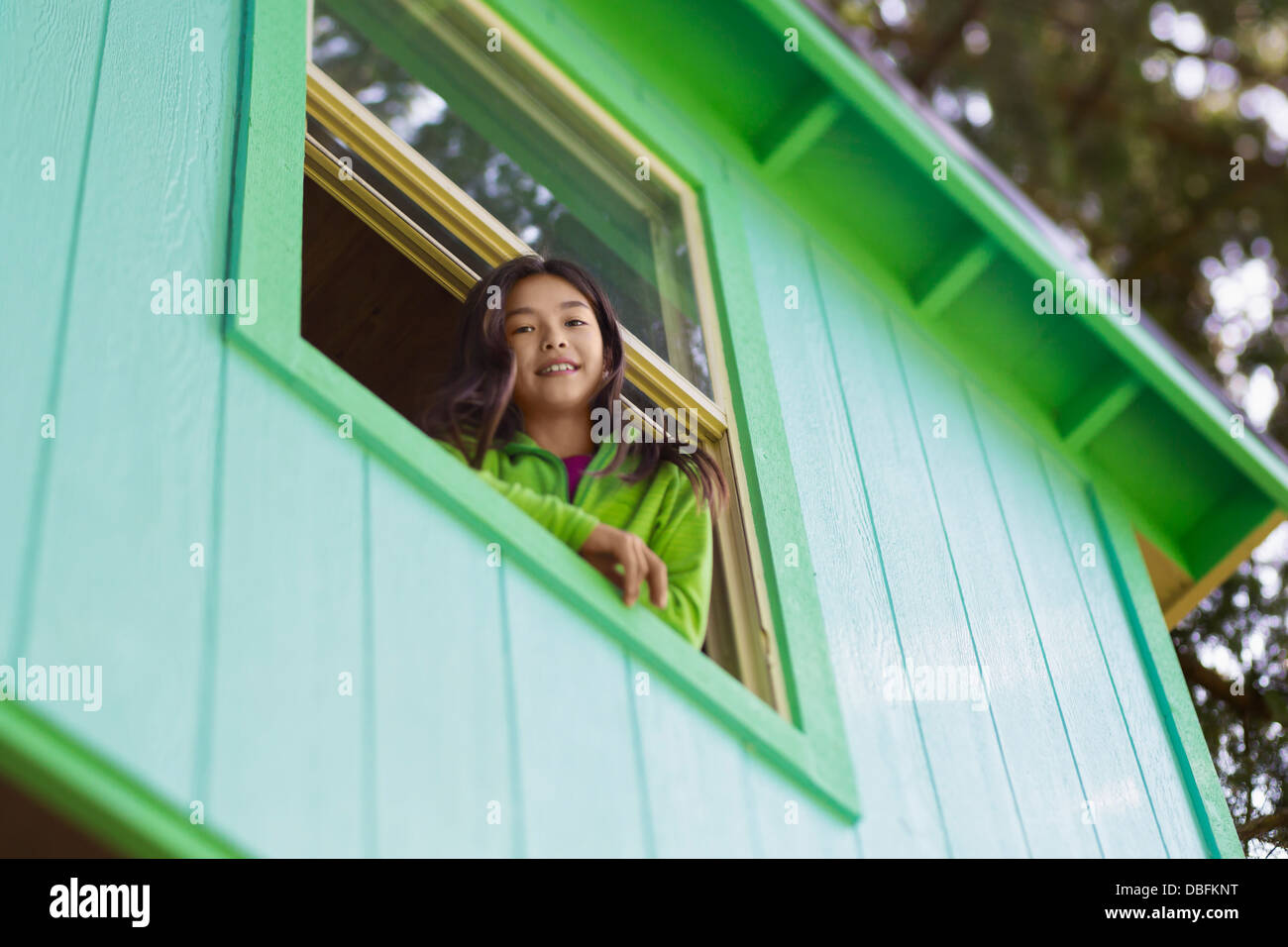 Mixed race girl leaning out window Stock Photo