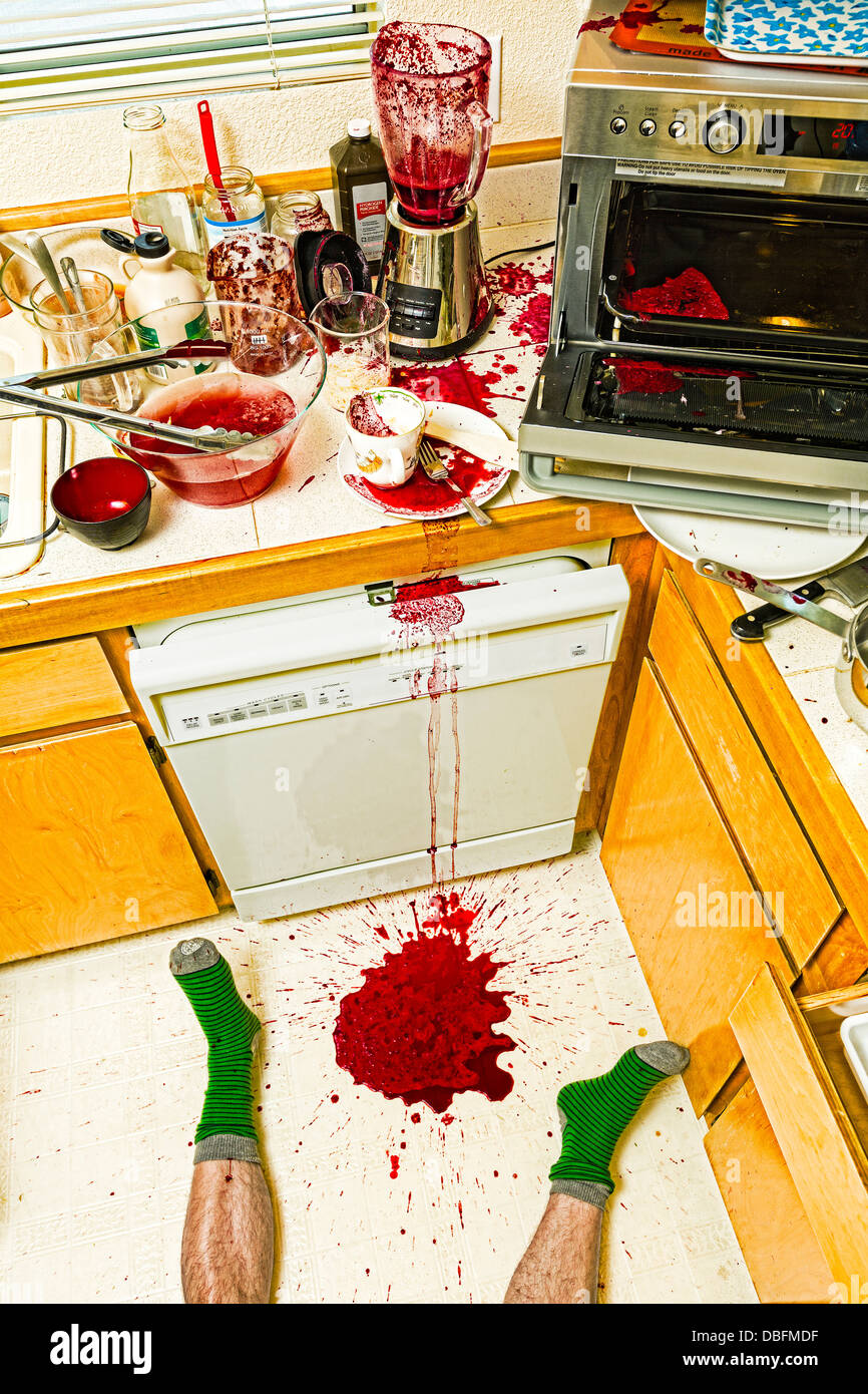 Man laying on floor in messy kitchen Stock Photo