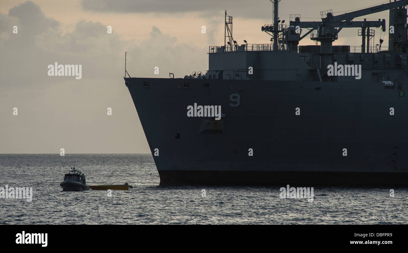 A rigid-hull inflatable boat (RHIB) from the amphibious dock landing ship USS Pearl Harbor (LSD 52) tows a disabled fishing vessel, carried from sea aboard the Military Sealift Command dry cargo and ammunition ship USNS Matthew Perry (T-AKO-9), to shore o Stock Photo