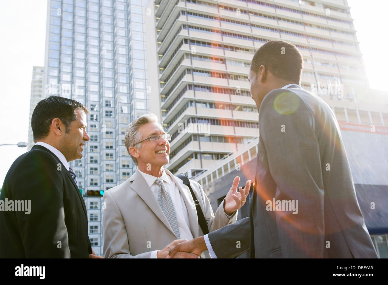 Businessmen shaking hands on city street Stock Photo
