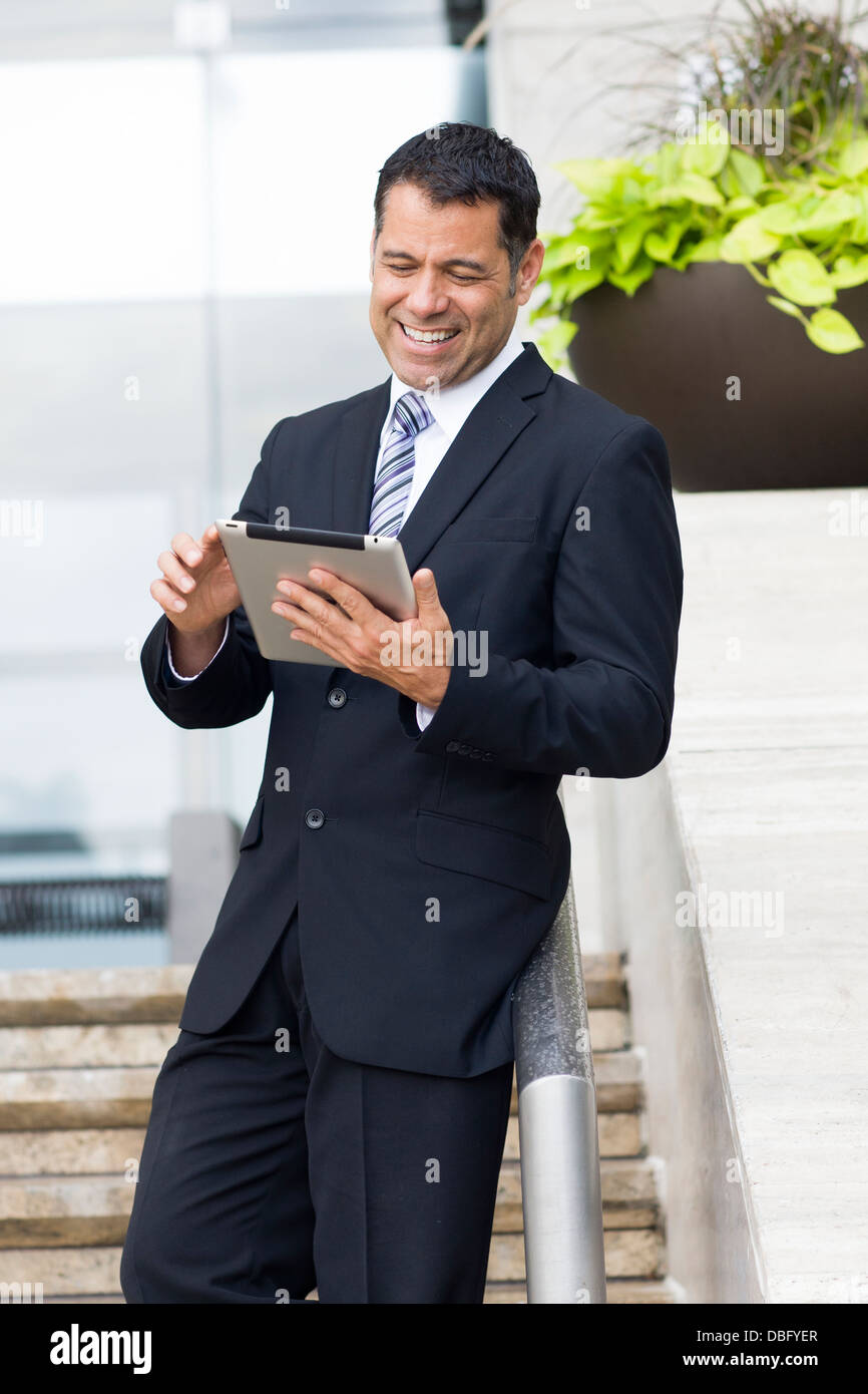 Hispanic businessman with tablet computer on city street Stock Photo