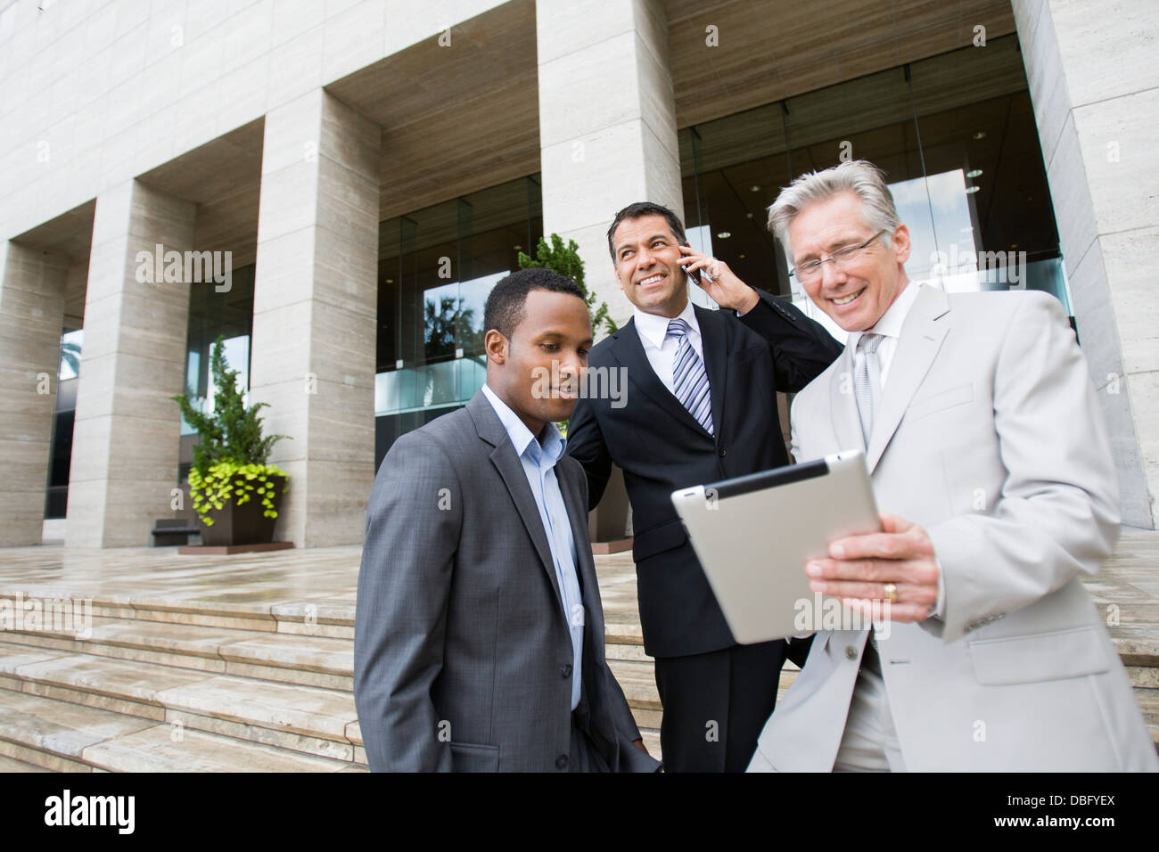 Businessmen using tablet computer on city street Stock Photo