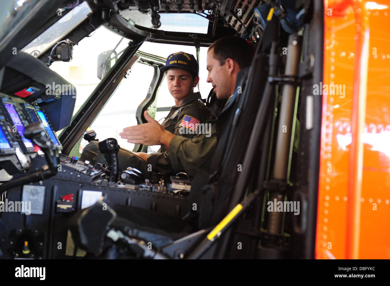 Lt. Kevin Winters, an Air Station Kodiak MH-60 Jayhawk helicopter pilot, explains the cockpit layout of the Jayhawk to Braeden Hahn, a resident of New Jersey and prospective Coast Guard helicopter pilot, at Air Station Kodiak, Alaska, July 24, 2013. Baead Stock Photo