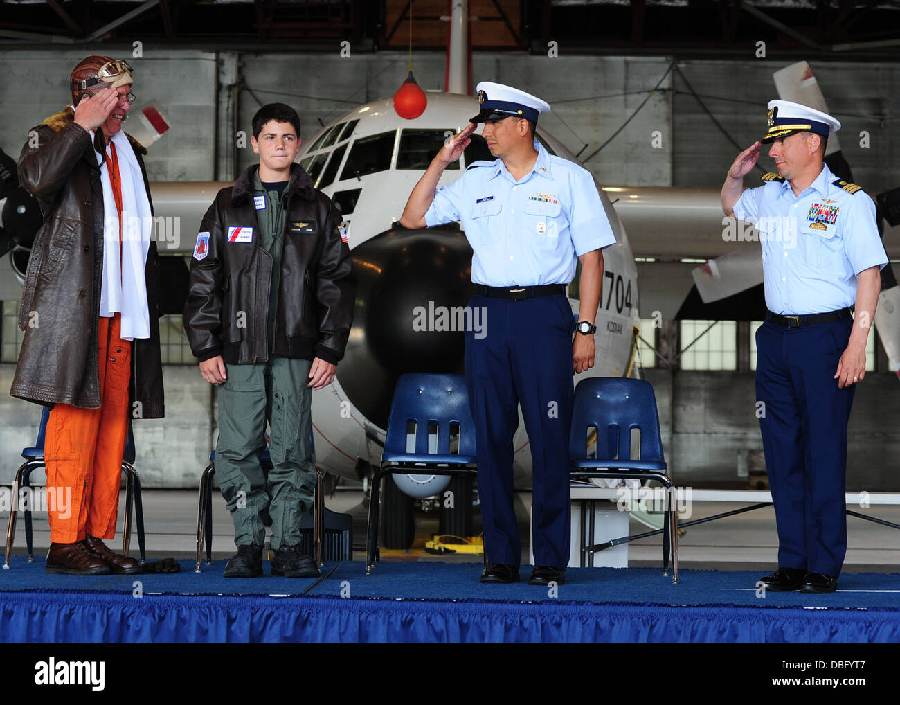 Braeden Hahn, a visitor to Coast Guard Air Station Kodiak sponsored by the Make-A-Wish foundation, is saluted by top ranking Air Station Kodiak officials at a wing-pinning ceremony in Kodiak, Alaska, July 25, 2013. The wing pinning ceremony is a high Coas Stock Photo