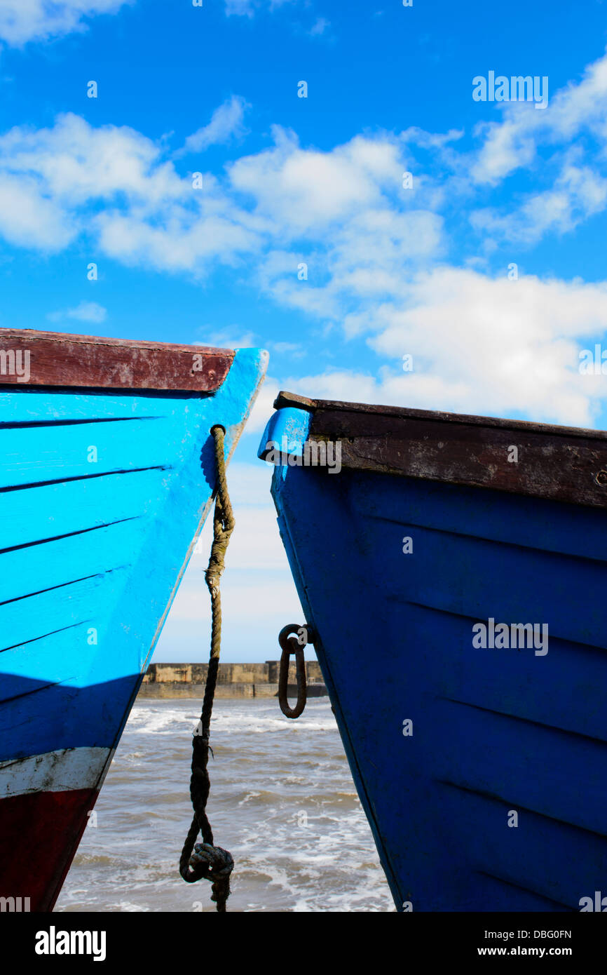 Two blue boats with water and blue sky in background Stock Photo