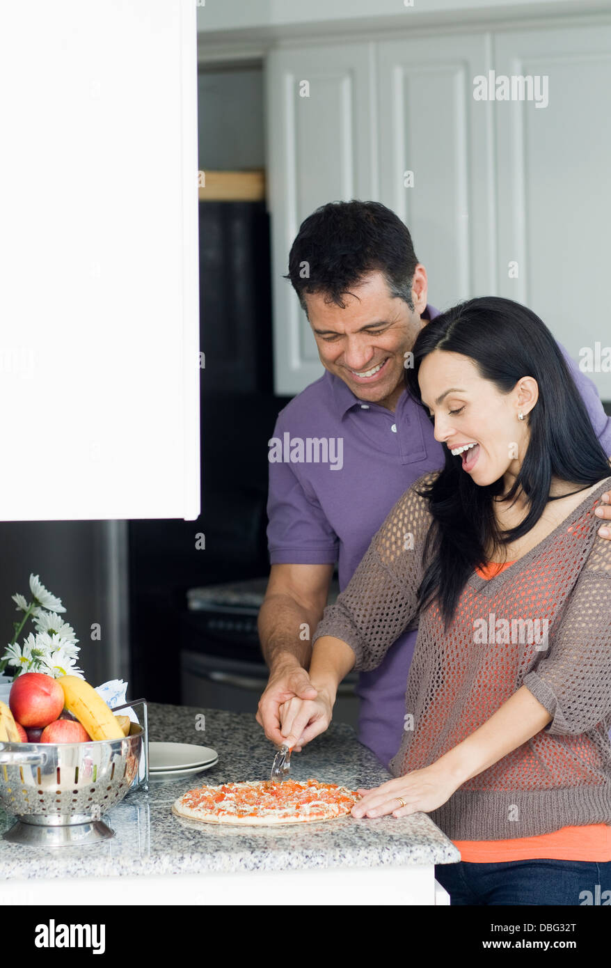 Hispanic couple cooking in kitchen Stock Photo