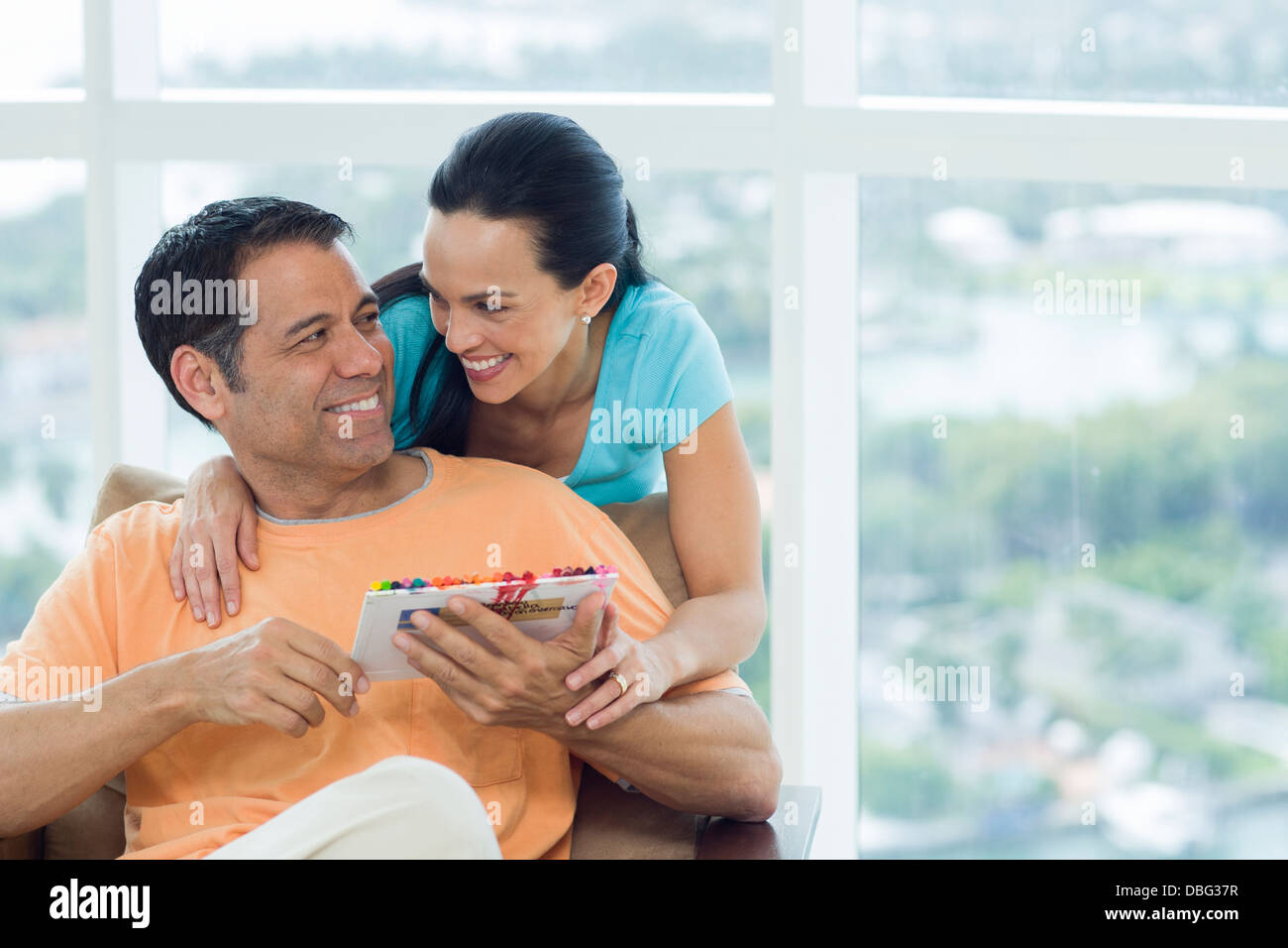 Hispanic couple hugging in armchair Stock Photo