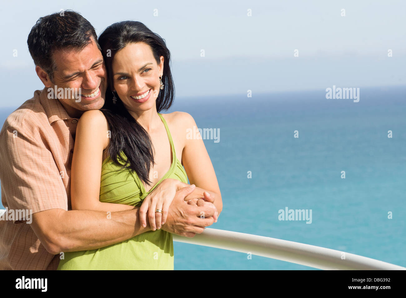 Hispanic couple hugging on boat deck Stock Photo