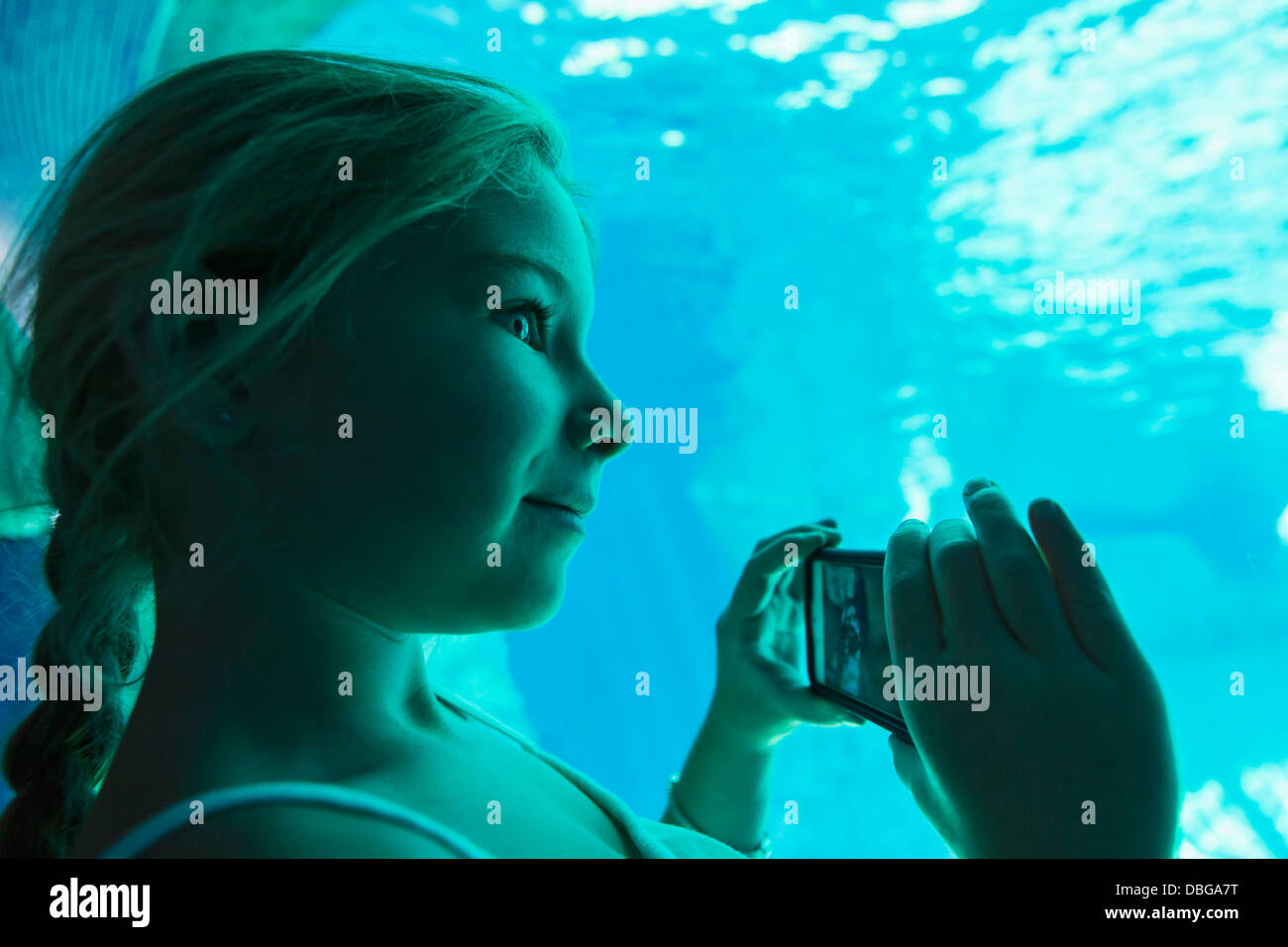 Caucasian girl taking pictures in aquarium Stock Photo