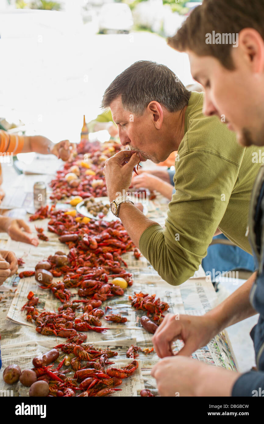Caucasian men eating at crawfish boil Stock Photo