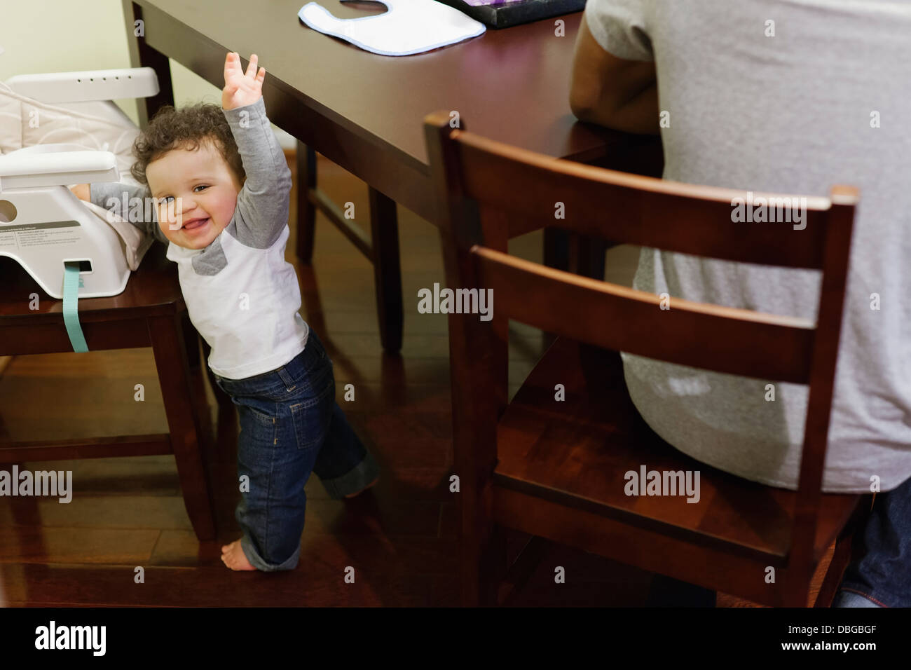 Baby climbing into high chair at table Stock Photo Alamy